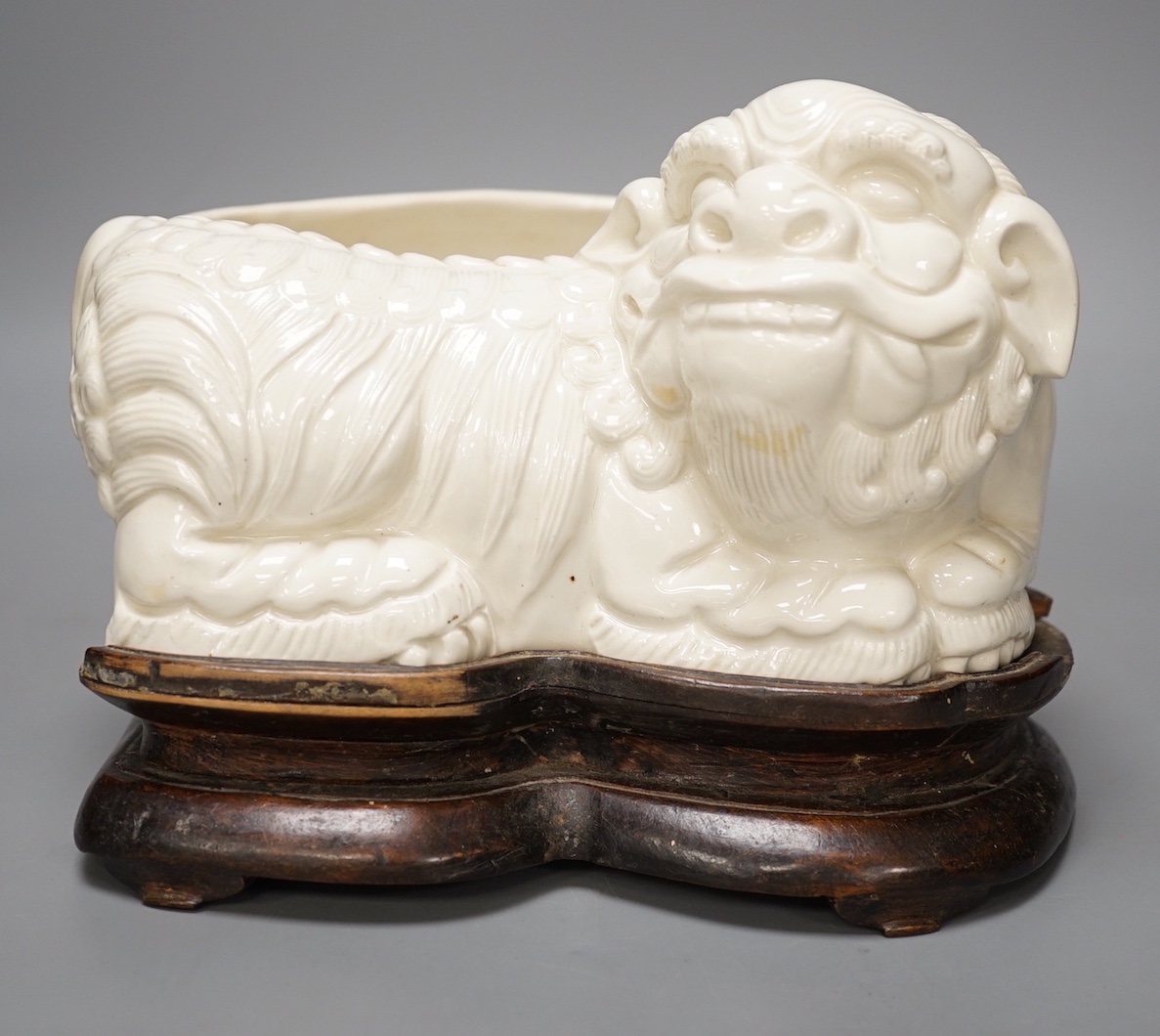 A Chinese cream glazed lion’dog planter on hardwood stand, 21cm